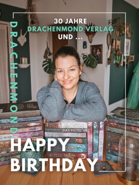 Autorin l&auml;chelnd auf dem B&uuml;cherstapel, der beim Drachenmond Verlag erschienen ist.